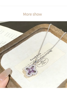 Detailed close-up of lucky four-leaf clover necklace with purple stones and diamonds