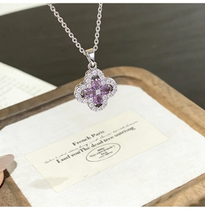 Macro shot of silver four-leaf clover necklace with purple stones and pavé diamonds