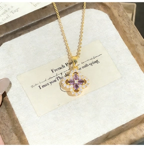 Detailed view of gold clover pendant featuring purple stones and sparkling crystals