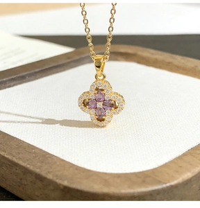 Macro view of gold four-leaf clover pendant with purple stones and micro-pave diamonds