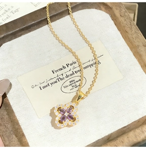 Macro shot of gold clover pendant with purple gemstones and white crystal detailing