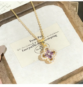 Macro shot of gold four-leaf clover pendant with purple stones and pavé diamonds