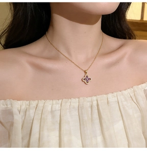 Macro view of purple gemstone clover pendant on a gold chain worn by a female model
