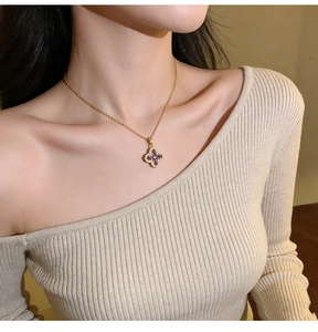 Detailed close-up of a purple four-leaf clover pendant necklace with diamond accents on a model