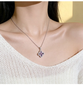 Close-up of a silver four-leaf clover necklace with purple stones and micro-pave diamonds