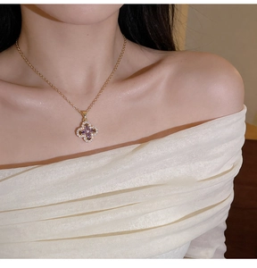 Detailed view of a gold clover necklace with purple stones worn by a model