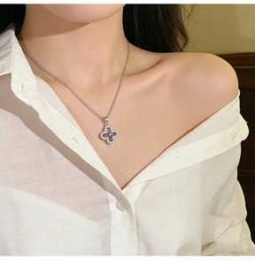 Close-up of woman wearing a clover necklace with purple stones and micro-pave crystals