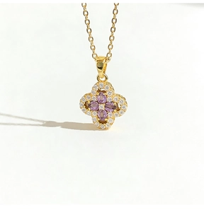 Detailed macro view of four-leaf clover pendant with purple stones and gold chain