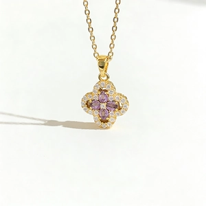 Golden clover necklace with purple stones and diamonds against a white background