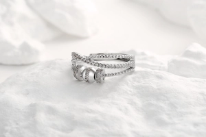 Detail shot of a silver spinning fidget ring with zircon stones on a white stone background