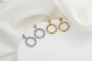 Détails des boucles d'oreilles créoles pavées de cristaux dorés et argentés sur soie blanche