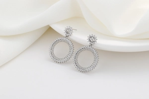 Détail de boucles d'oreilles cercles en argent avec zircons sur tissu texturé blanc