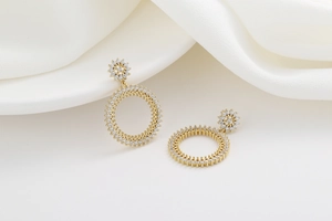 Détail macro de boucles d'oreilles créoles dorées avec zircons étincelants pavés