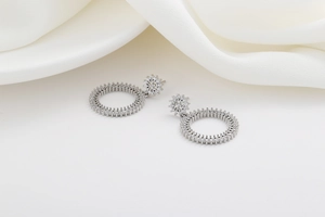 Détail macro de boucles d'oreilles pendantes argentées avec pierres étincelantes