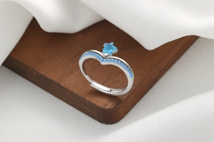 Macro shot of silver-tone V-shaped open ring with blue star gem and pave blue stones
