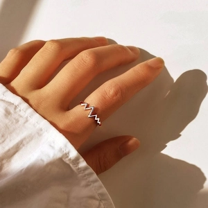 Rose gold heartbeat ring featuring a creative EKG wave design worn on index finger