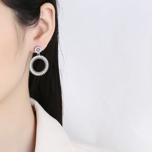 Boucles d'oreilles créoles en argent serties de cristaux scintillants portées par un mannequin