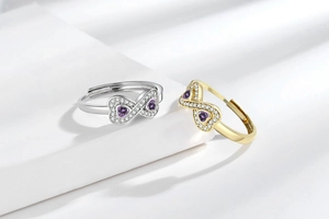 Dettagli di due anelli infinito con pietre a cuore viola in oro e argento
