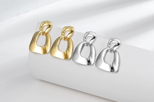 Detail of minimalist 18K gold and silver geometric link earrings on display stand