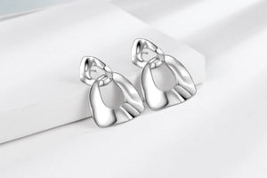 Close-up of polished silver geometric earrings with irregular trapezoid drop pendants