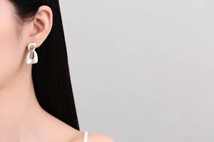 Detail view of silver geometric hollow earrings with matte finish on a female model