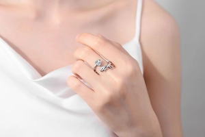Detail of silver whale ring with heart-shaped stone and dolphin motif on a finger