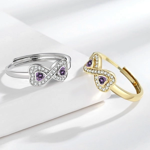 Anelli infinito oro e argento con zirconi a cuore viola e pavé di diamanti su fondo bianco