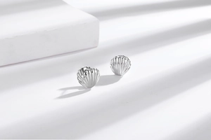 Detailed view of silver shell stud earrings with polished finish and striped shadow effect