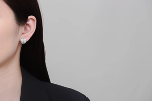 Detailed view of striped shell-shaped earrings in polished silver on a model's ear