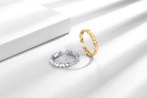 Close-up of interlocking hollow heart open rings in silver and 18k gold finishes
