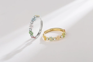 Detail of gold and silver rings featuring colorful enamel flowers and pavé zircons