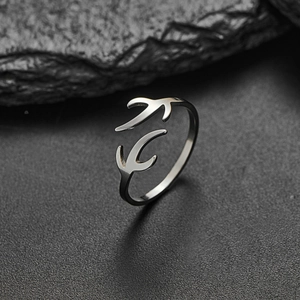 Minimalist silver swallow open ring with polished metal birds on a dark stone background