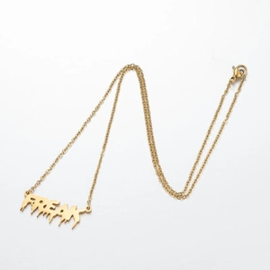 Vue rapprochée du pendentif doré FREAK au design fluide sur une fine chaîne en métal