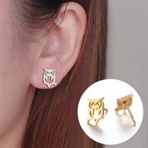 Boucles d'oreilles hibou évidées en argent et or portées par un mannequin