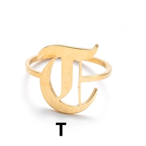 Detailaufnahme eines gotischen Buchstabens T auf einem goldenen Edelstahlring im Minimal-Stil