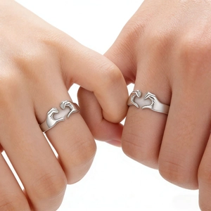 Minimalist silver heart hands couple rings shown in a pinky swear gesture on white background