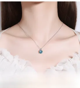 Macro detail of female neck wearing blue heart crystal pendant on silver chain
