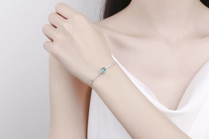 Close-up of elegant silver bracelet with a blue gemstone and white zircon on a wrist