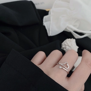 Close-up of adjustable silver heart ring with zircon stone worn on finger