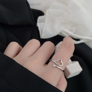 Detail of adjustable open ring featuring hollow heart and single zircon on model hand