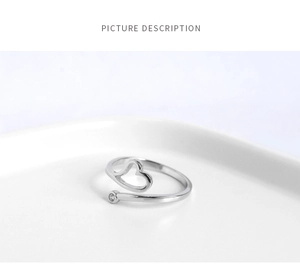 Detailed close-up of a silver open heart ring with a sparkling cubic zirconia on a white tray