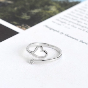 Minimalist silver heart open ring with a single clear zircon on a white background