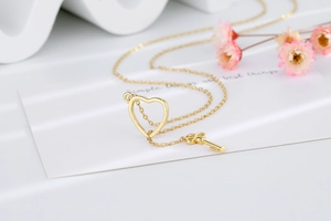 Detail of gold key and hollow heart pendants on a delicate adjustable chain necklace