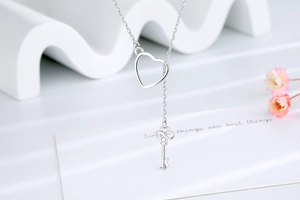 Close-up of silver lariat necklace with heart slider and infinity symbol key pendant