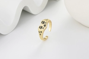 Détail d'une bague coeur dorée ajustable avec motif visage triste noir artistique