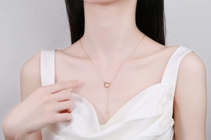 Detail of adjustable gold key necklace with heart ring pendant worn by model on silk top