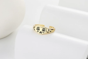 Gros plan sur la bague dorée en forme de cœur avec motif de visage qui pleure