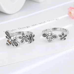 Adjustable bee and daisy spinning rings with cubic zirconia on white ceramic tray