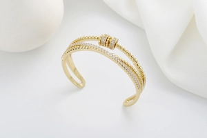 Detail of a gold double-layered cuff bracelet featuring zircon inlay and round bead charms