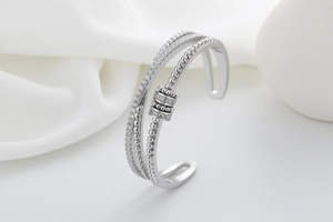 Detailed macro view of multi-layer silver bangle with cubic zirconia pavé and moving bead